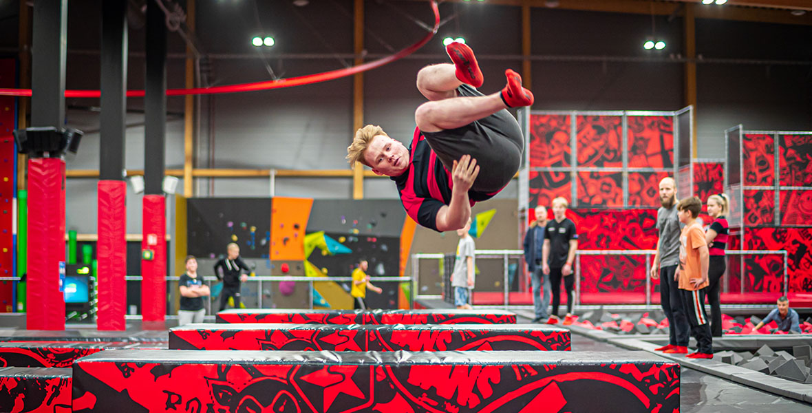 En ung mann i luften, hoppande på studsmatta i trampolinparken