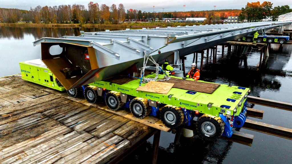 Limegrønne SPMT-plattformer benyttes for å montere broelementer til ny bro over vannet i Karlstad, Sverige.