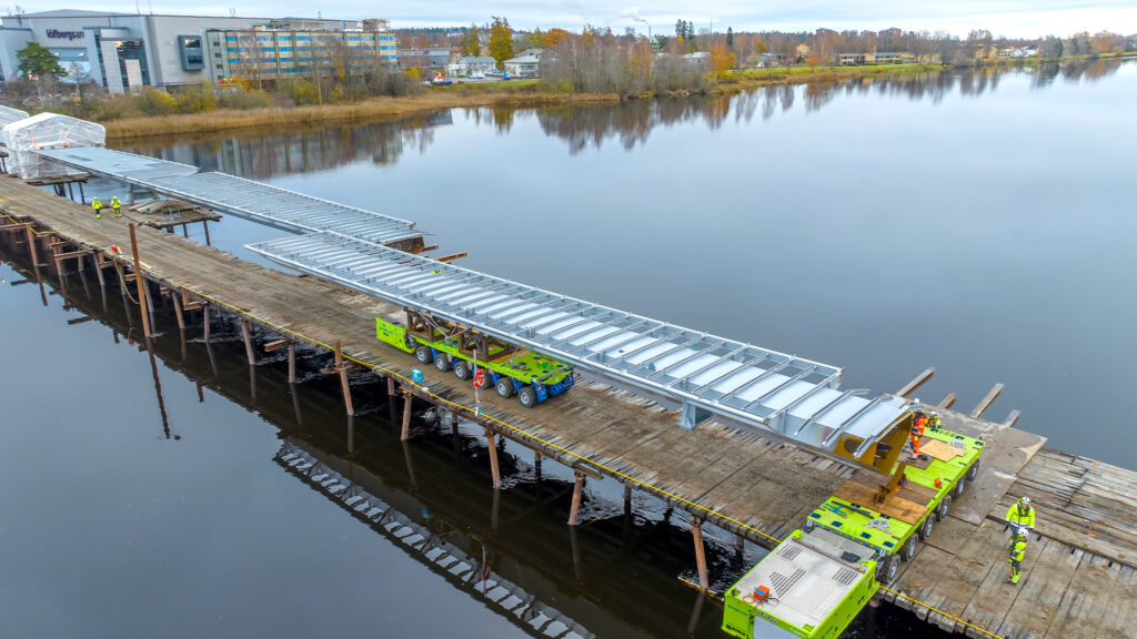 Limegröna SPMT-plattformar fraktar broelement för att bygga ny bro över älven i Karlstad.