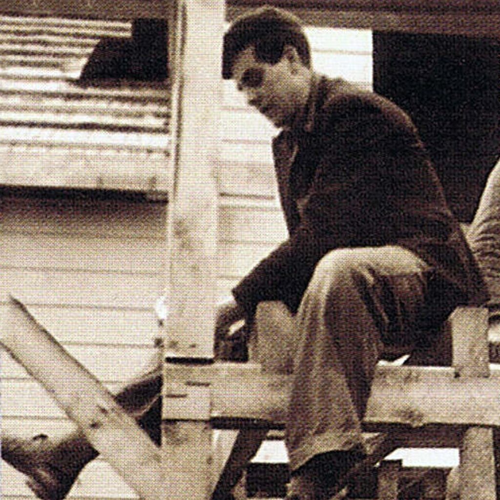 Svartvitt foto från 1950-talet av Bjarne Kynningsrud, sittande och snickrar med hammare